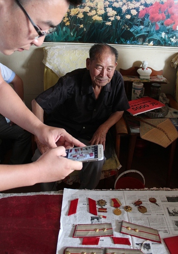 8月21日，一师塔建集团一名团员在用手机拍摄抗战老战士曹来昌的军衔、奖章等老物件。